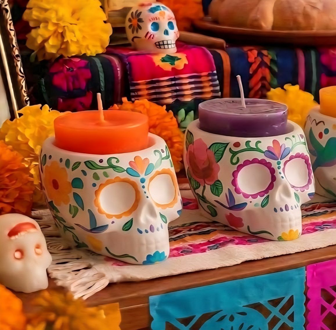 Portavelas de calavera blanca decorados y pintados a mano con flores coloridas sobre ofrenda de Día de Muertos. Portavelas de calavera blanca decorados y pintados a mano con flores coloridas sobre ofrenda de Día de Muertos.